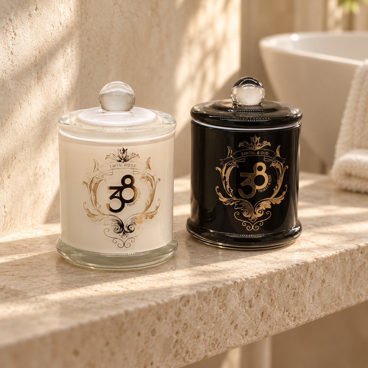 Bloom & Desire candle duo, with white Twin Rose and black Santal & Oud jars together on an ivory stone shelf