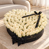 White fresh roses in a black heart-shaped Madame de Fleur box on a sunlit stone table
