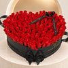 Red fresh roses in a black heart-shaped Madame de Fleur box with black satin ribbon, against an ivory arch