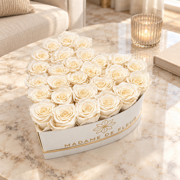 Large white heart box with ivory preserved roses on a marble coffee table