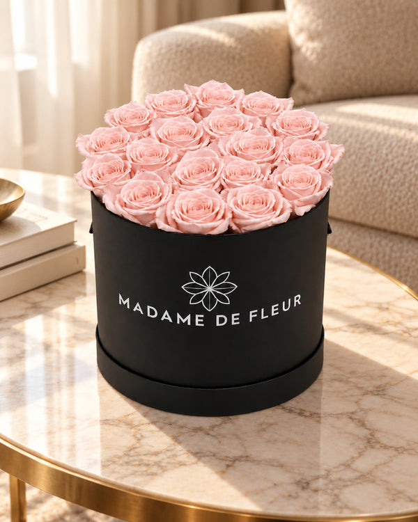 Medium Black Round Box with blush preserved roses on a marble table in a luxury hotel sitting room